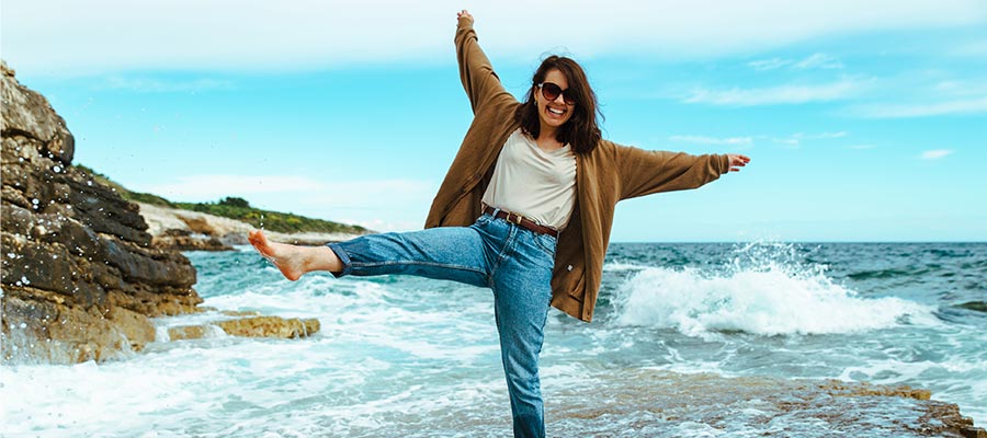 Gesunde, lächelnde Frau springt im Meer – Ausdruck von Lebensfreude und Vitalität im Alter.